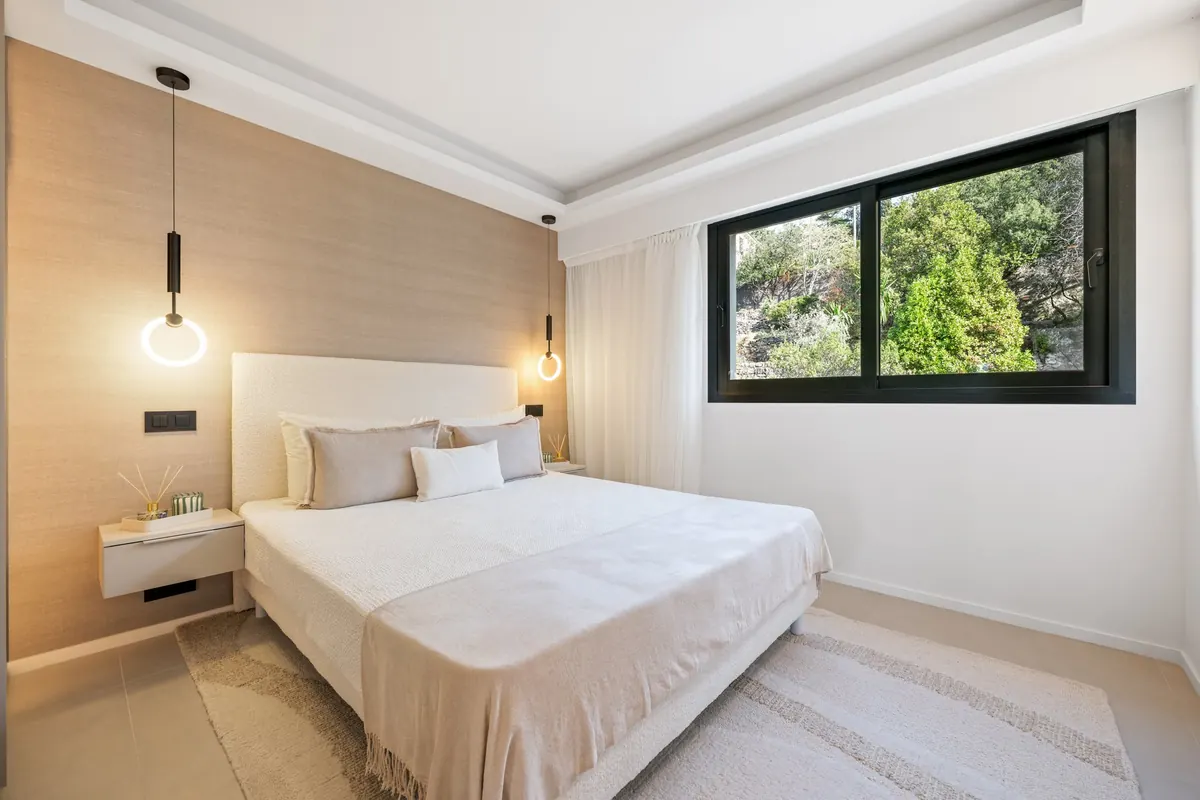 Chambre lumineuse aux boiseries claires avec grande baie vitrée, dans un appartement rénové du Mont-Boron