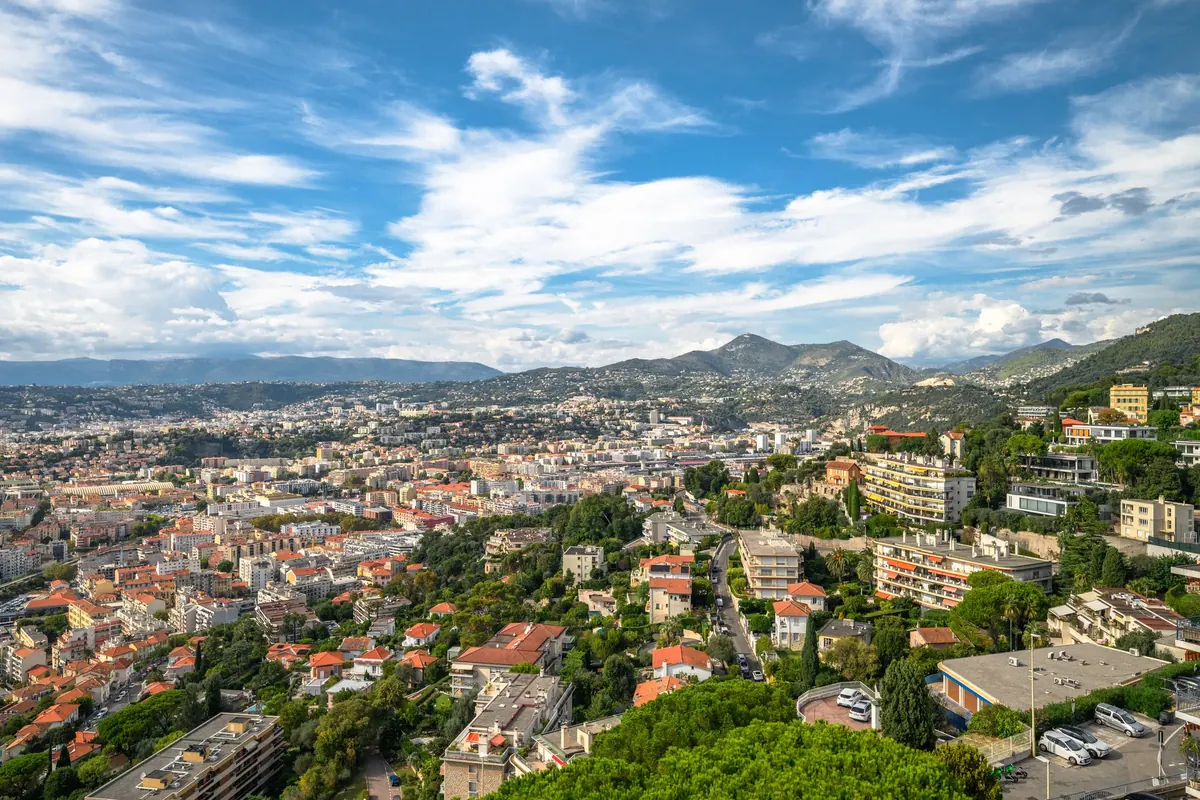 Vue sur les collines, les quartiers et le littoral de Nice sous un ciel dégagé, depuis la terrasse d'un appartement du Mont-Boron
