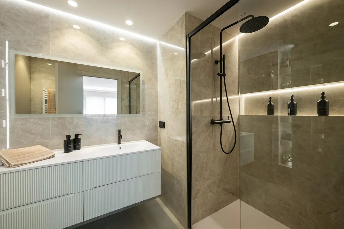 Bagno con ampia doccia a filo pavimento, lavabo bianco e specchio illuminato, nell'appartamento Le Vert Boron
